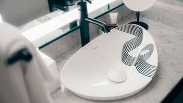 A bathroom sink with a modern design, a soap dispenser, and a mirror.