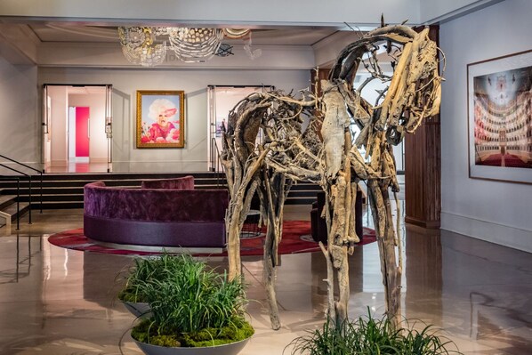 A lobby with a central art installation, a staircase, and a seating area.