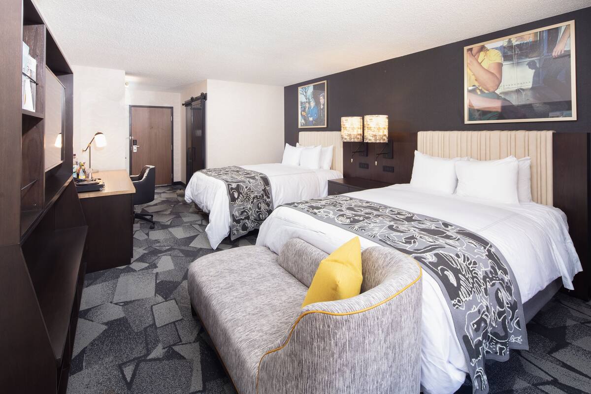 Une chambre d’hôtel avec deux lits, un bureau et un canapé.