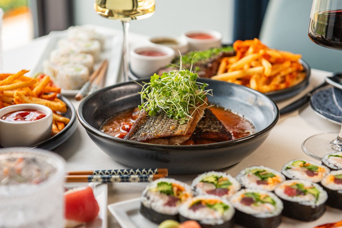 Un assortiment de plats comprenant des sushis, des frites et un bol de soupe garni de poisson.