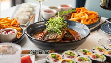 Un assortiment de plats comprenant des sushis, des frites et un bol de soupe garni de poisson.