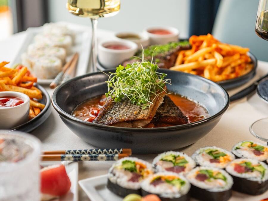Un assortiment de plats comprenant des sushis, des frites et un bol de soupe garni de poisson.