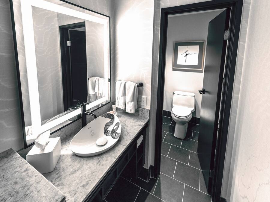 Un bagno moderno con uno specchio grande, un lavabo con un porta sapone e un water.