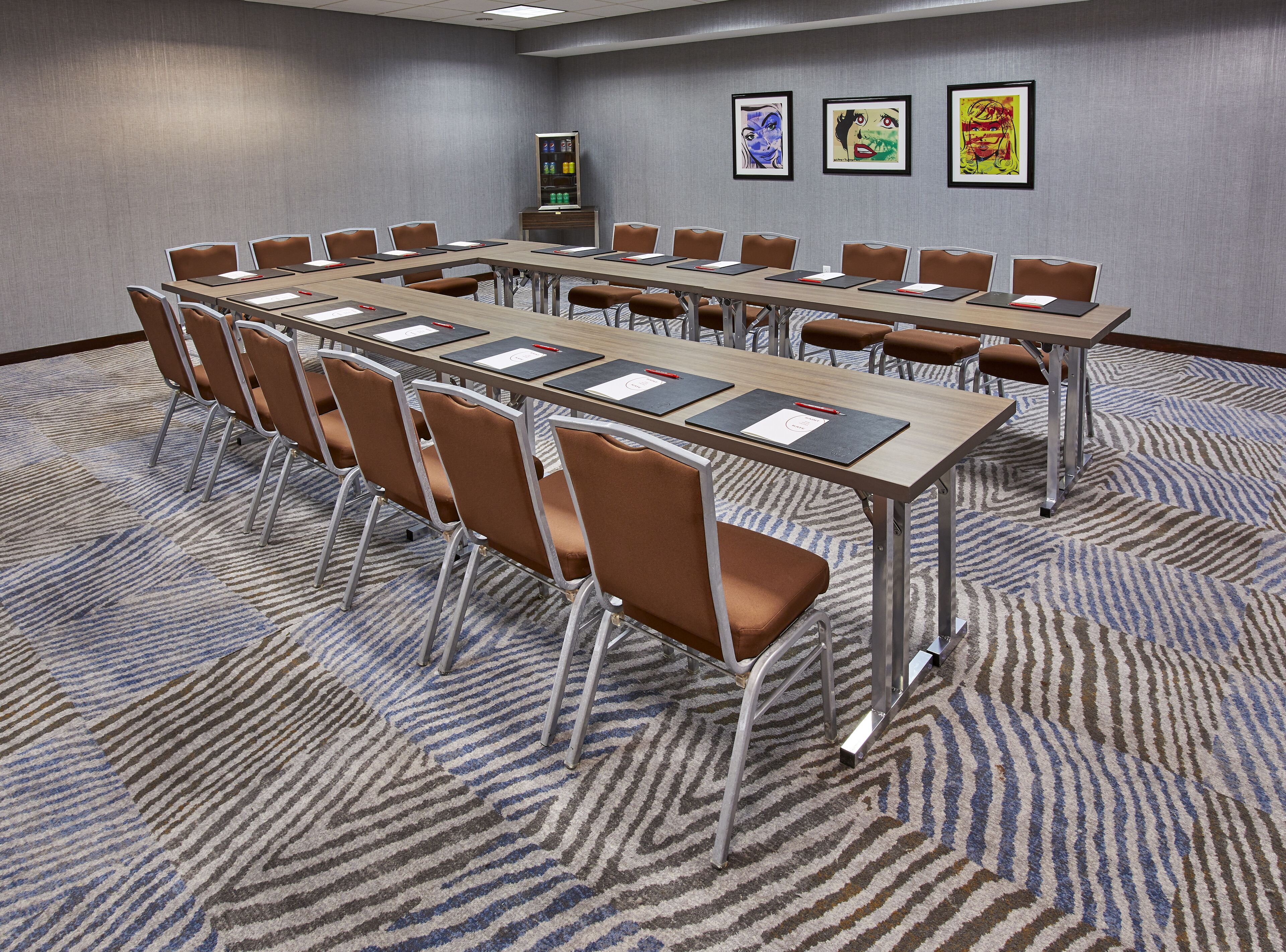 A conference room with a long table, brown chairs, and a carpeted floor.