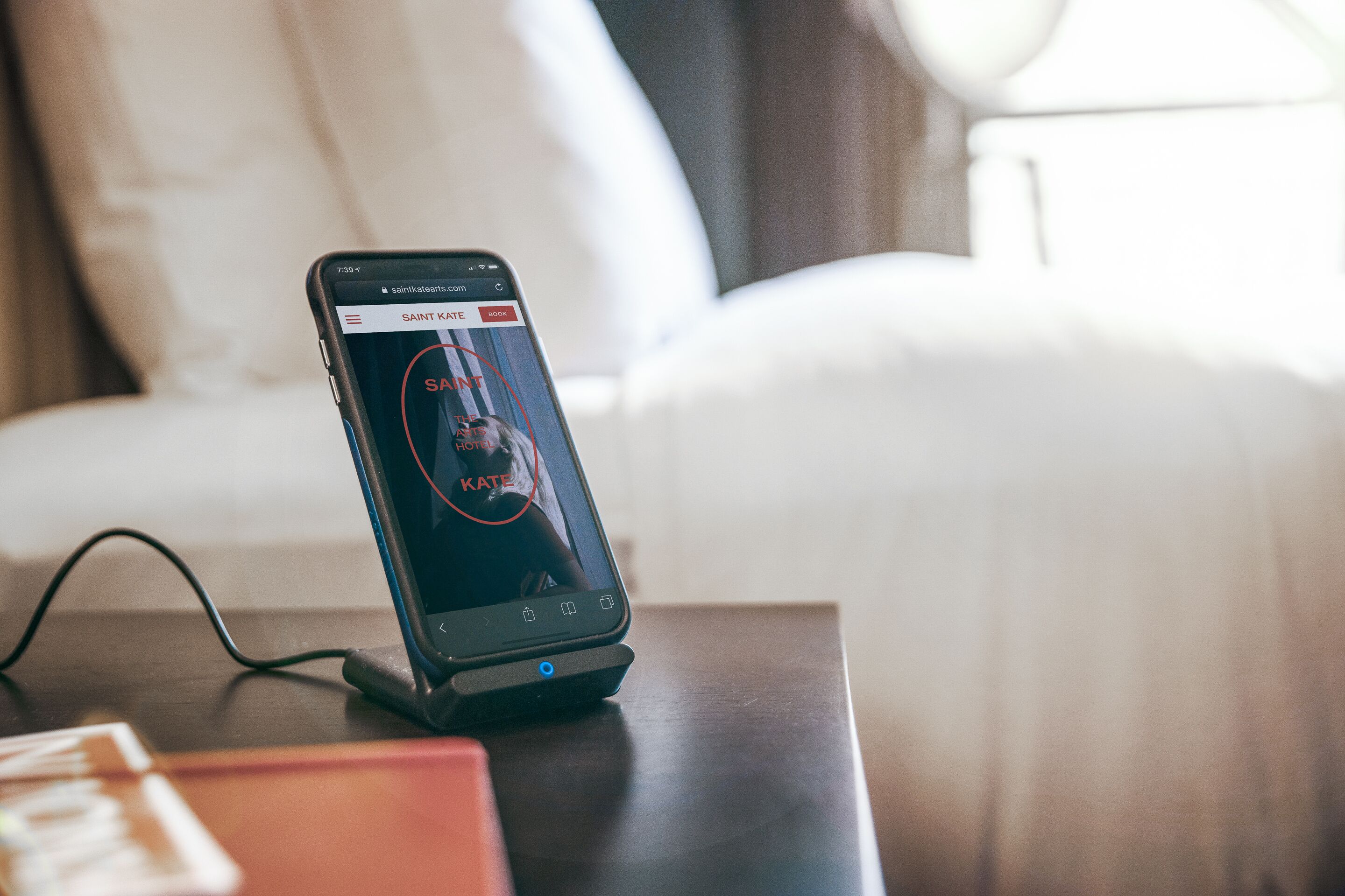 A smartphone on a charging dock in a hotel room.