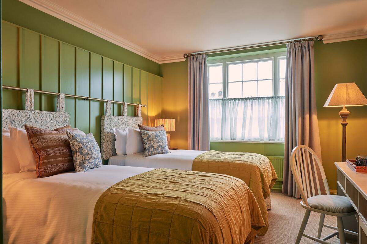 A hotel room with two beds, a desk, and a chair.