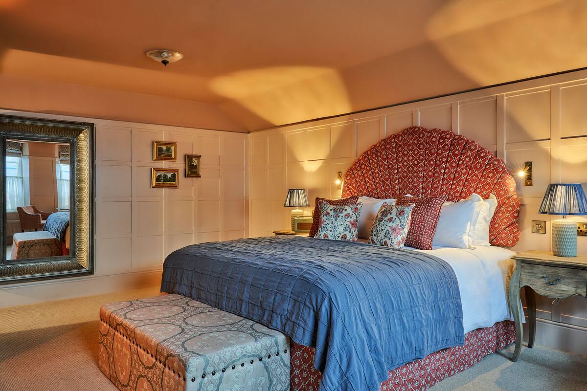A bedroom with a large bed, a mirror, and a decorative headboard.