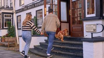 Un pub llamado 'The White Horse', con una puerta de madera y escalones que lo conducen.