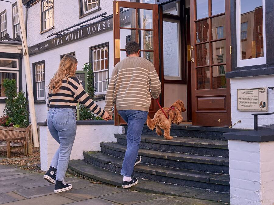 Un pub llamado 'The White Horse', con una puerta de madera y escalones que lo conducen.