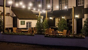 A building with outdoor seating and string lights. - The White Horse - A Heartwood Inn (Dorking)