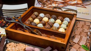 A variety of chocolates and desserts in a wooden box, with a pair of scissors on top.