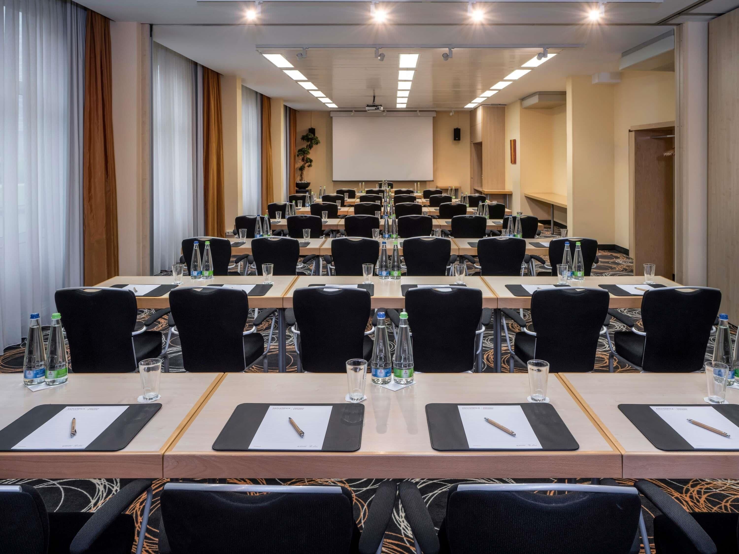 A conference room with multiple tables, chairs, water bottles, and nameplates.