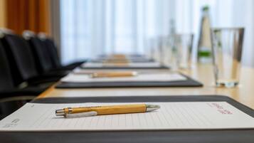 Une salle de conférence avec une longue table, des blocs-notes et des stylos disposés sur la table.