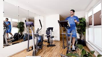Un gimnasio moderno con equipo de ejercicio, ventanas amplias y plantas de interior.