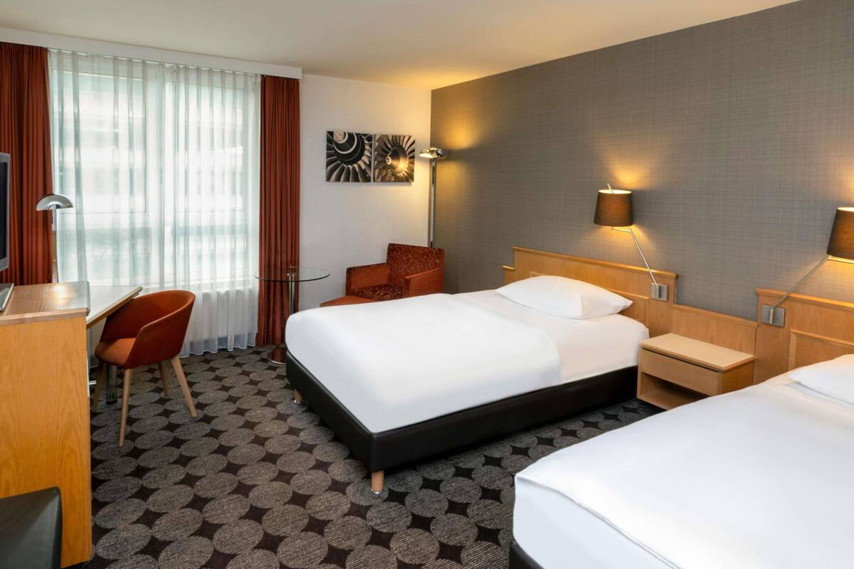 Ein Hotelzimmer mit einem großen Bett, einem Schreibtisch mit Stuhl, einem kleinen Tisch und einer Couch.