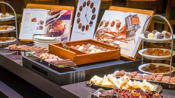 A buffet with various desserts and chocolates displayed on trays and stands.