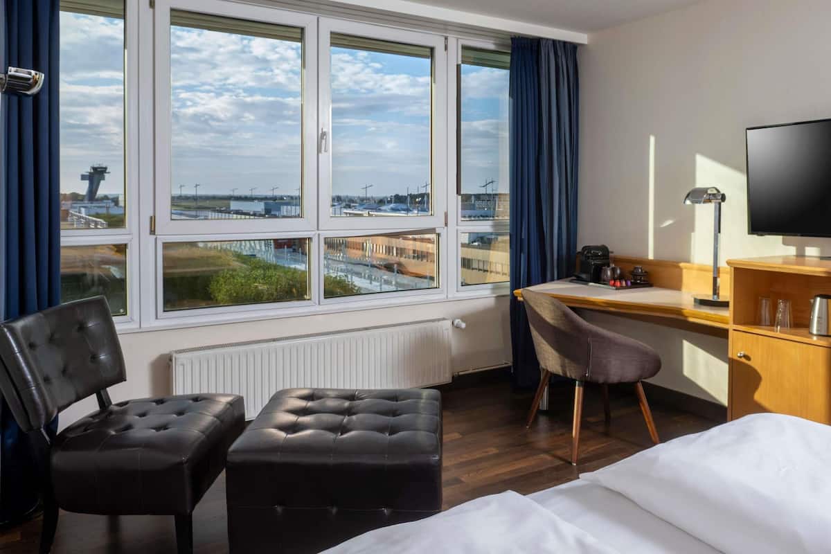 Ein Hotelzimmer mit Bett, Schreibtisch, Stuhl und Fernseher.