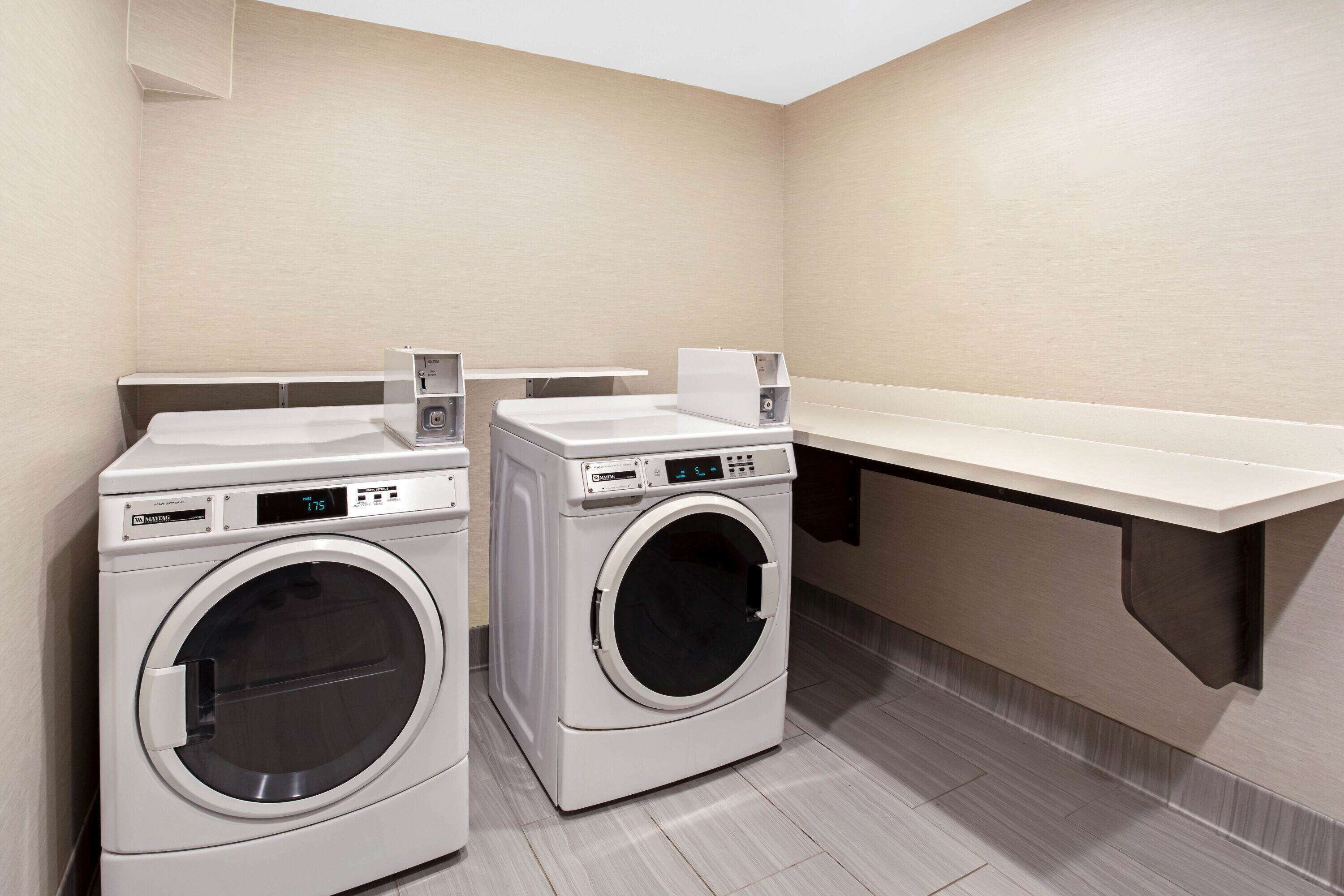 A laundry room with two front-loading washing machines and a white countertop.