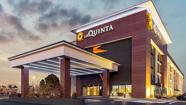Un hotel moderno con un llamativo letrero de 'La Quinta', una entrada cubierta y una fachada bien iluminada.