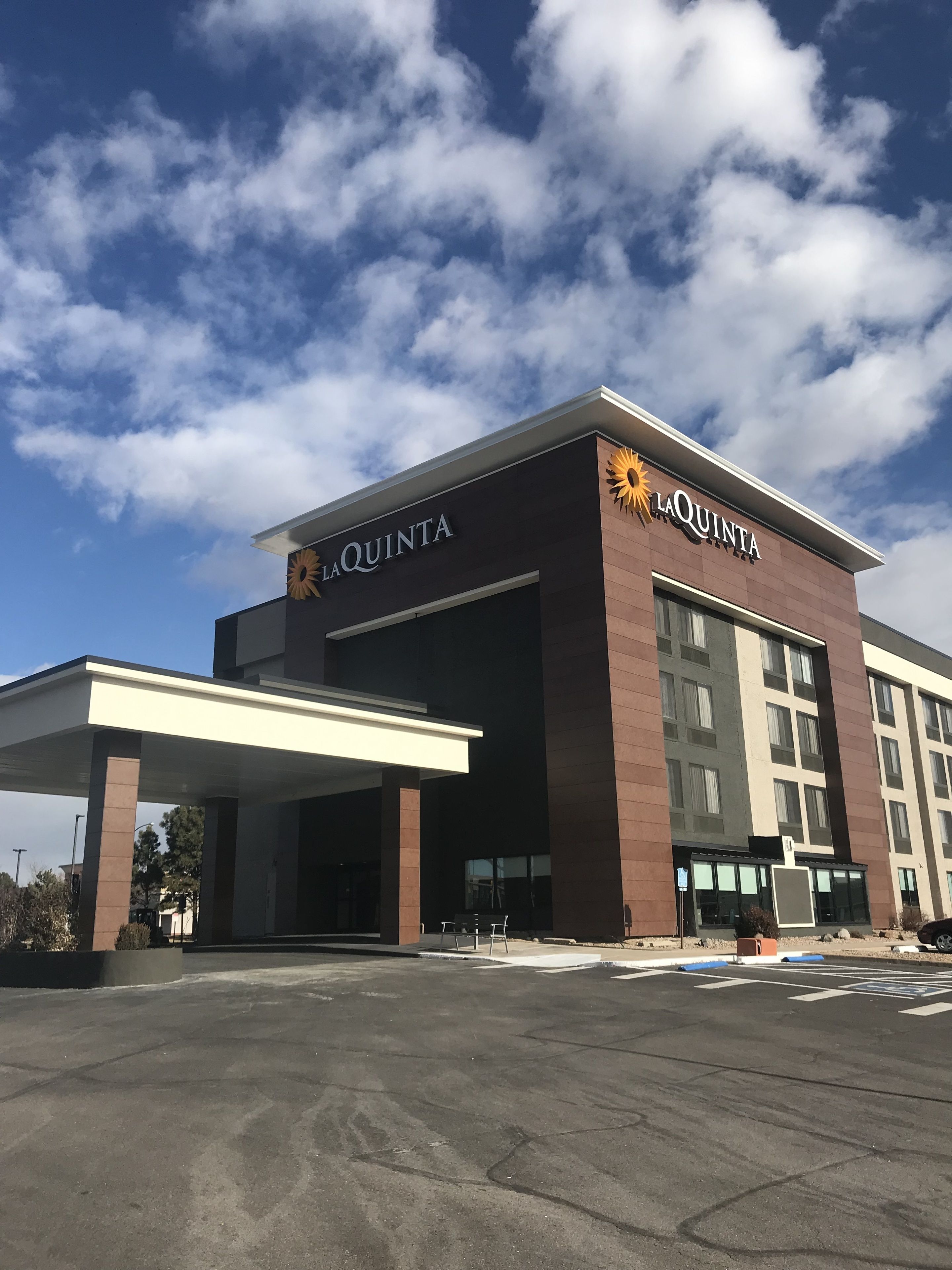 A La Quinta hotel with a modern design, a covered parking area, and a clear sky.