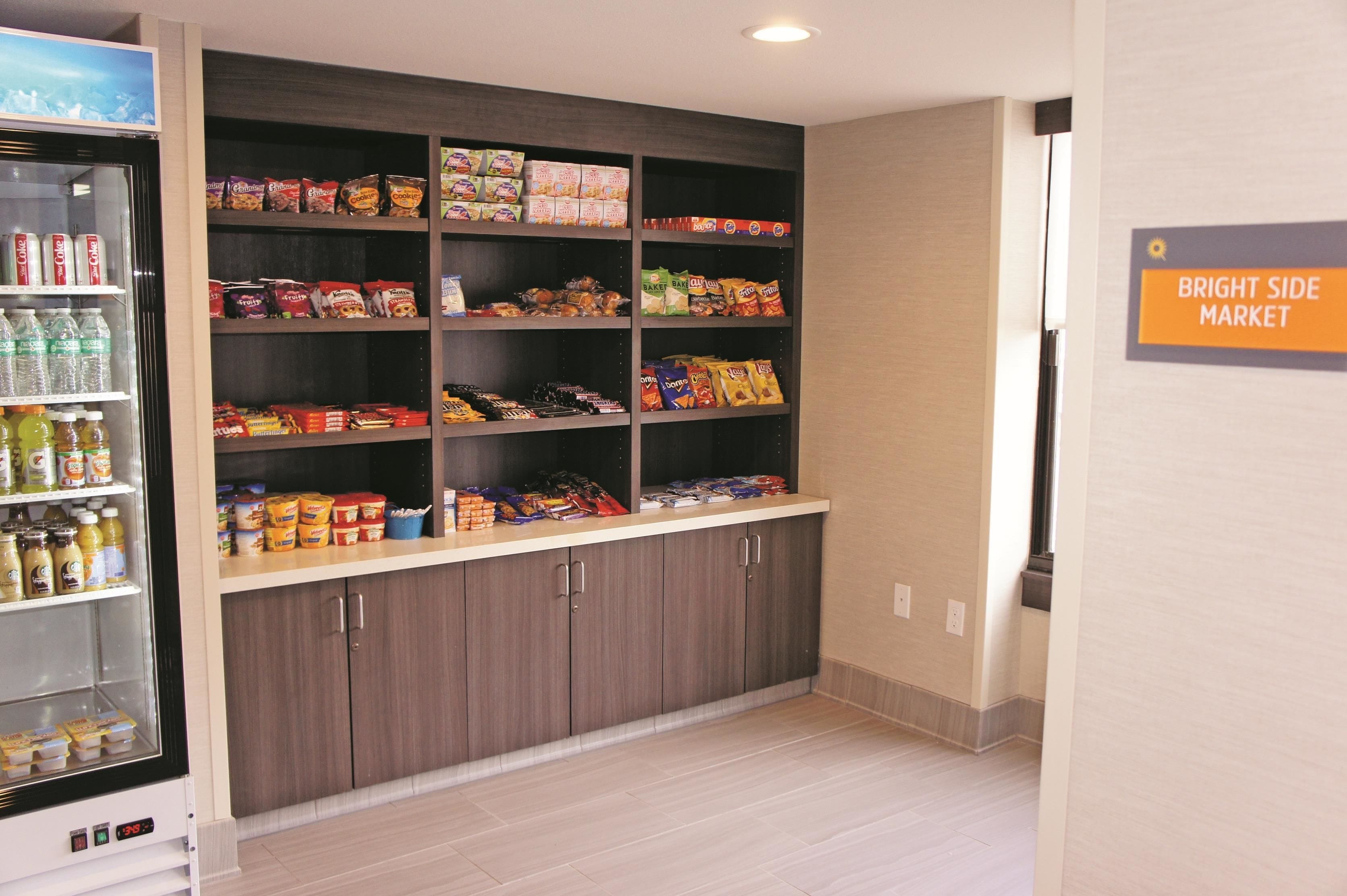 A kitchenette with a refrigerator, pantry shelves stocked with snacks, and a sign indicating the Bright Side Market.