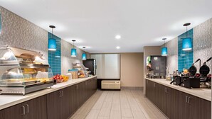Una cocina moderna con montaje tipo bufé, incluyendo una estación de autoservicio con diversos alimentos y una estación de café con equipo para prepararlo.