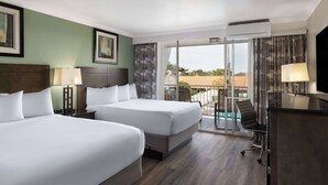 Une chambre d’hôtel avec deux lits, un bureau, une chaise et un balcon avec vue.