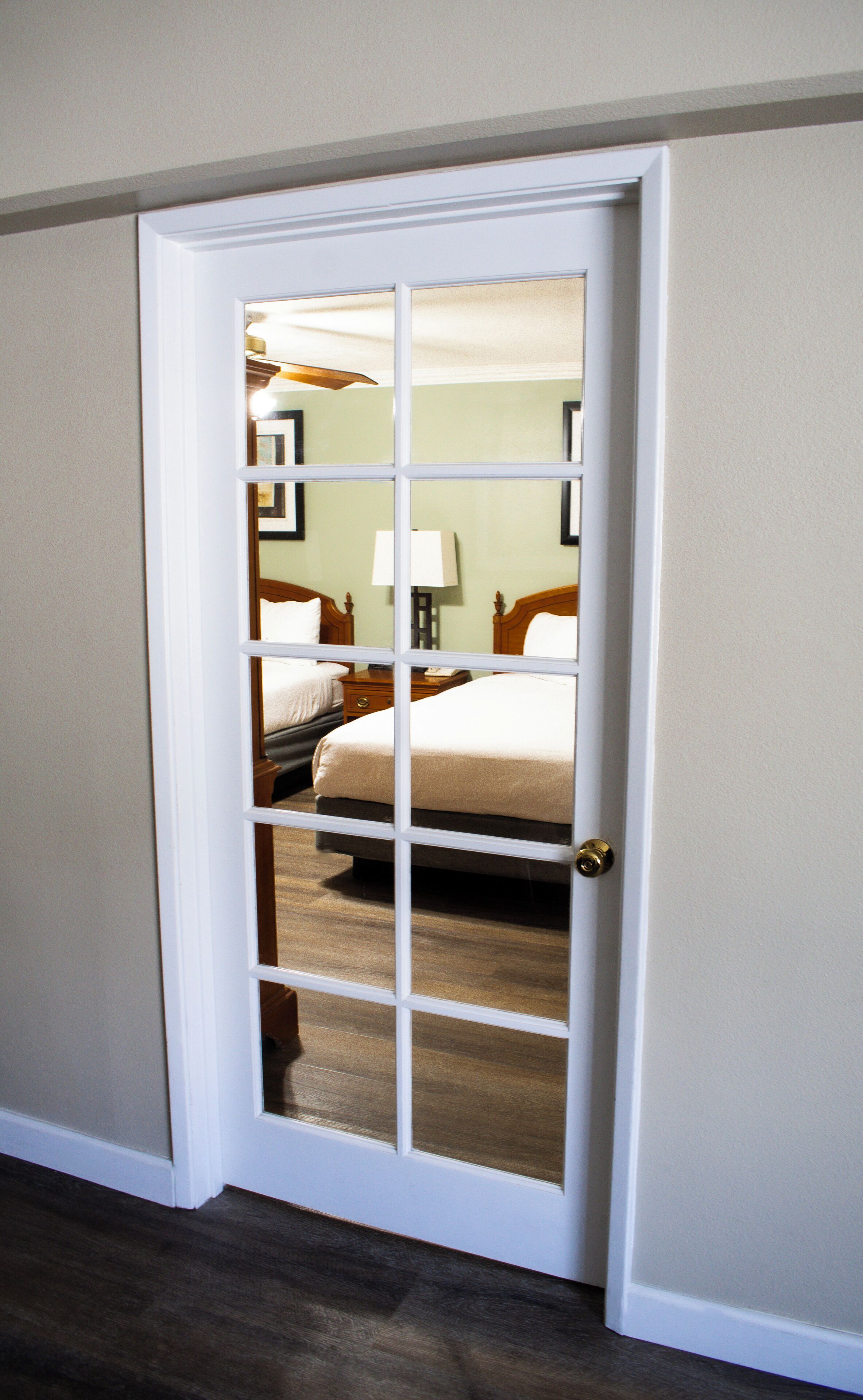 A hotel room with a large window, a bed, a nightstand, and a lamp.