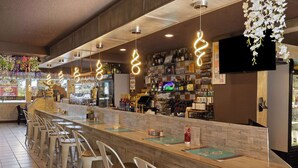 Un espace bar doté d’un long comptoir, de plusieurs tabourets et d’un écran de télévision fixé au mur.