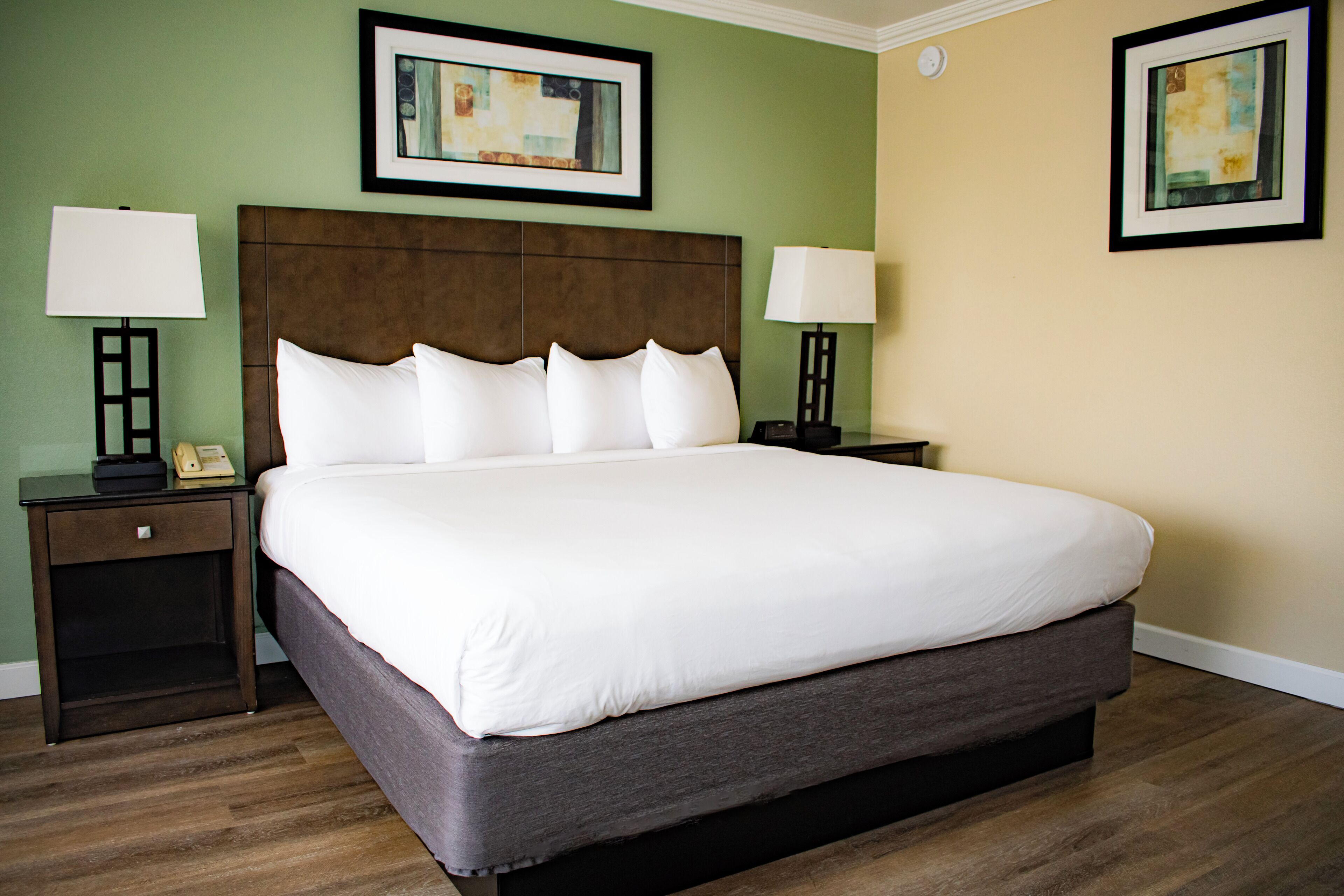 A hotel room with a large bed, two bedside tables, and two wall-mounted lamps.