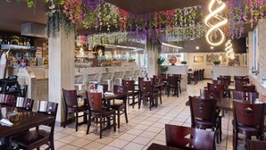 Un restaurant doté d’un bar, de tables et de chaises en bois, de plantes suspendues et d’un luminaire en forme de spirale.