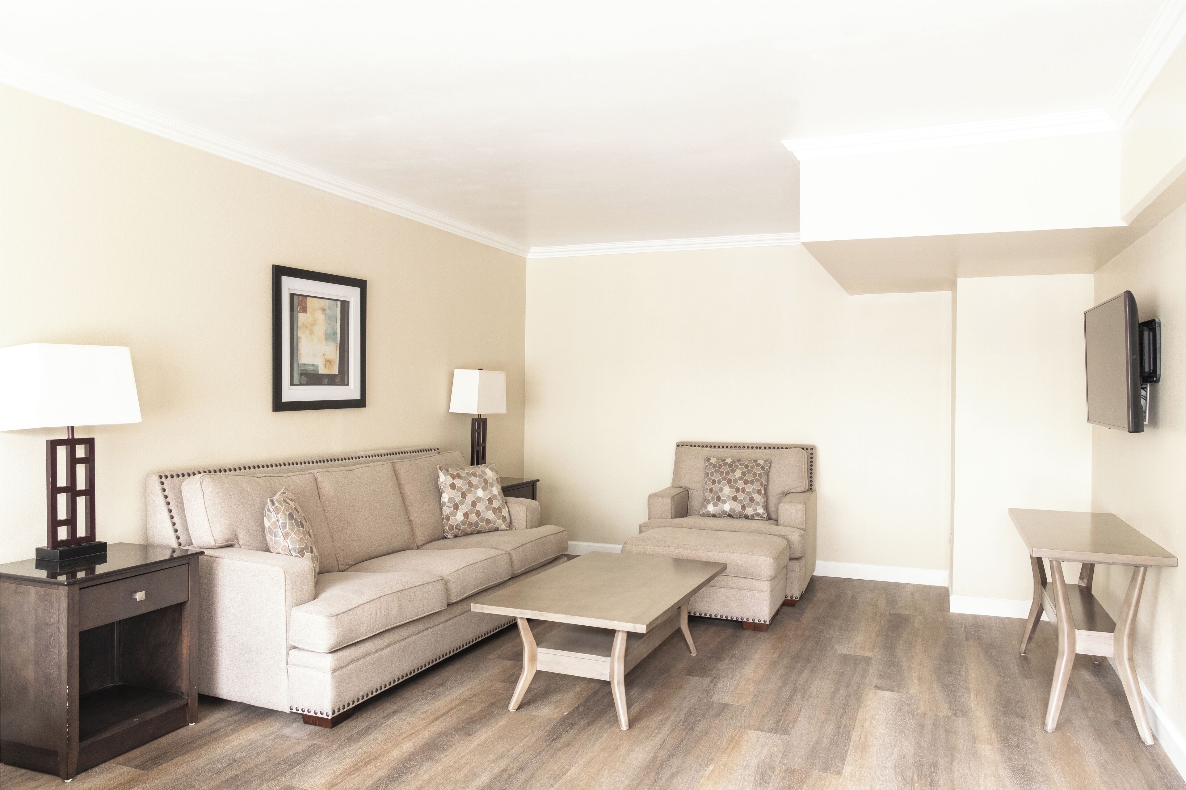 A living room with a sofa, two armchairs, a coffee table, a TV, and a lamp.