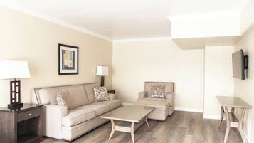 A living room with a sofa, two armchairs, a coffee table, a TV, and a lamp.