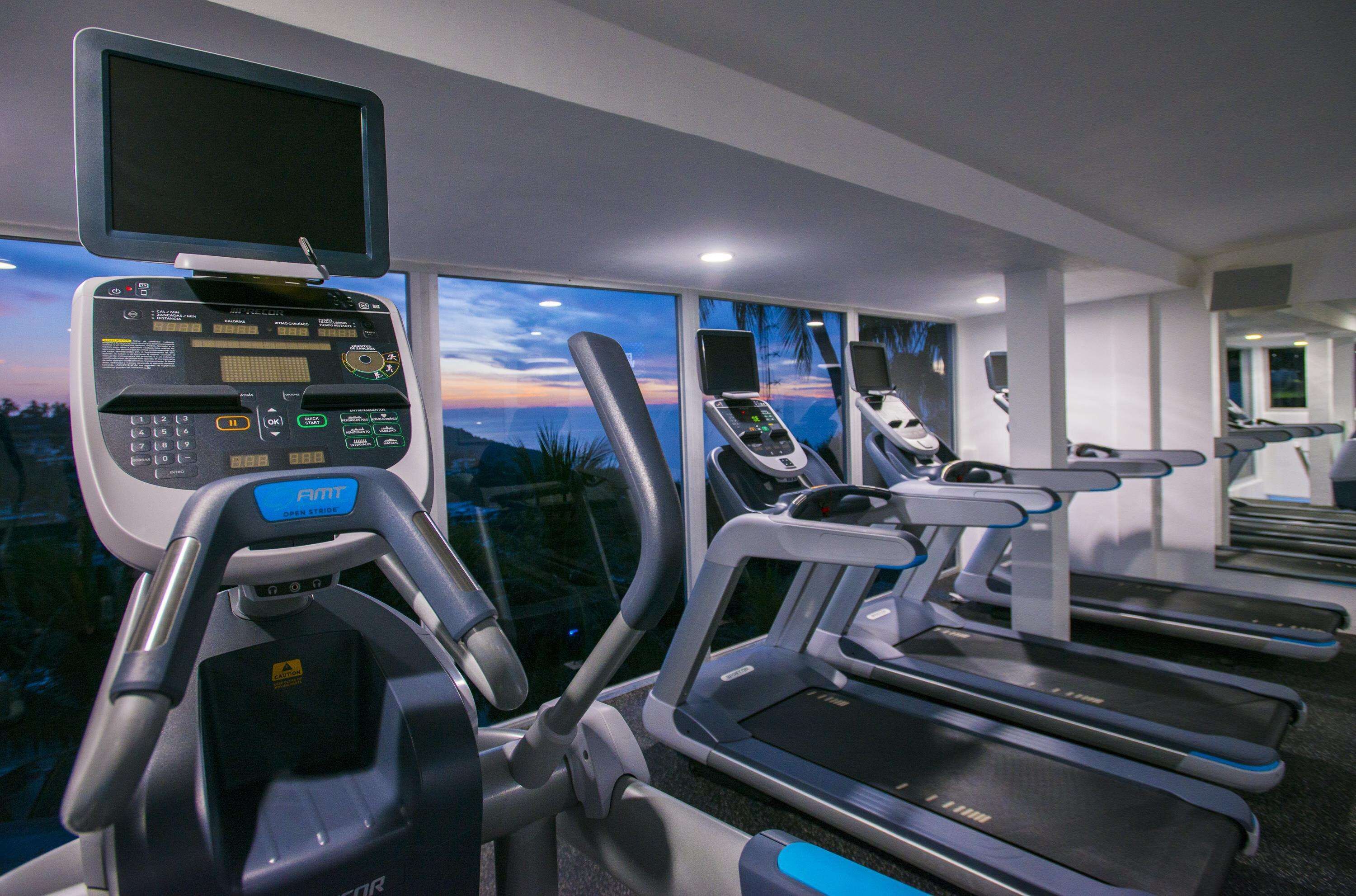 A gym with treadmills, a stationary bike, and a rowing machine.