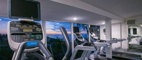 A gym with treadmills, a stationary bike, and a rowing machine.