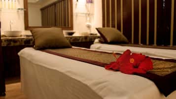 A hotel room with two beds, a large mirror, a sink, and a red flower on the bed.