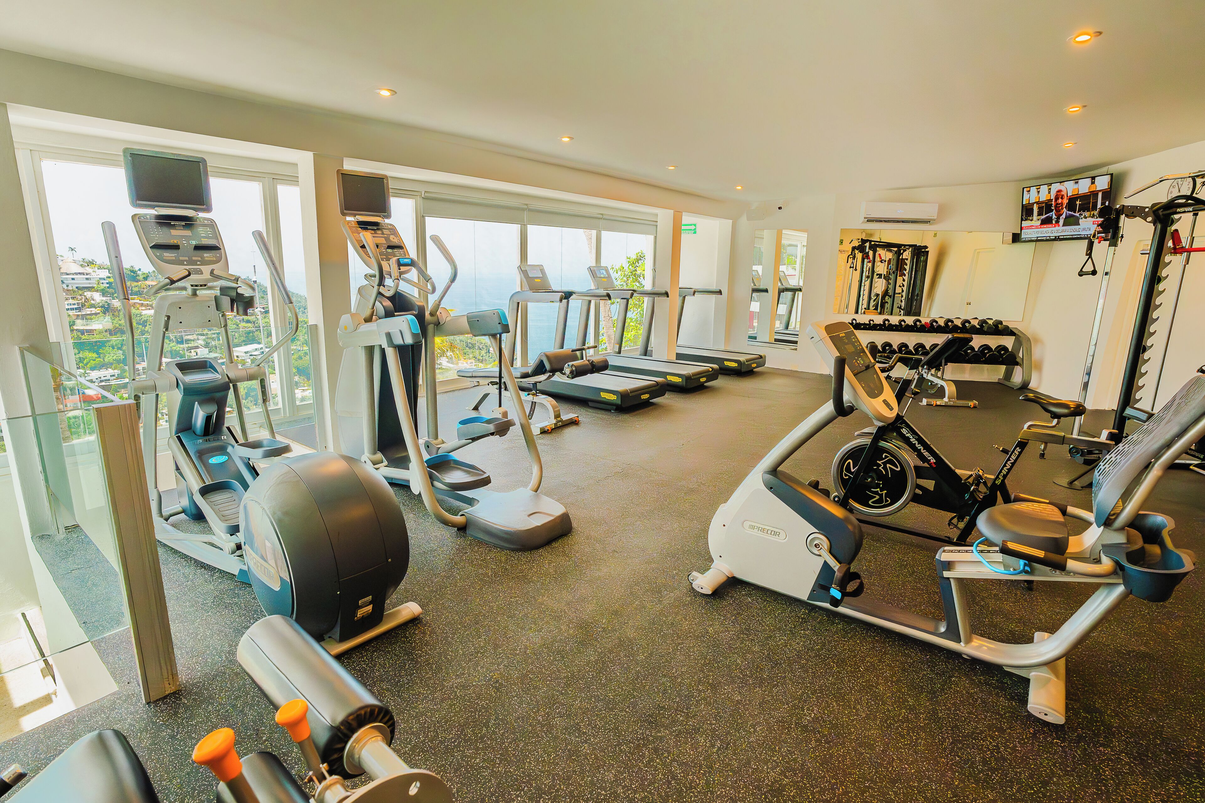 Un gimnasio con cintas de correr, elípticas y máquinas de pesas.
