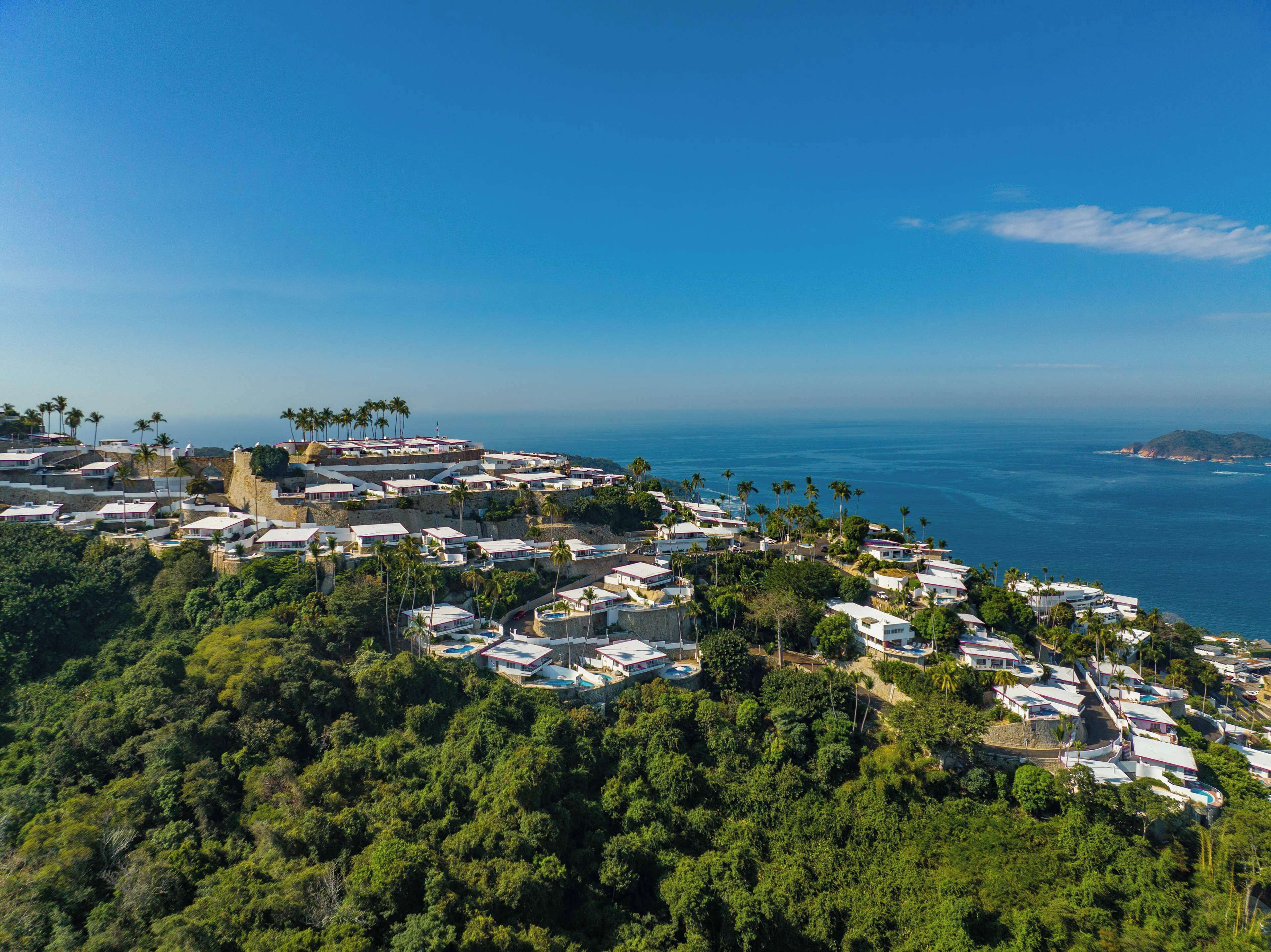 A coastal resort with multiple bungalow-style accommodations, a central courtyard, and a view of the ocean.