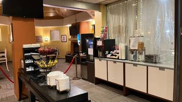 A hotel reception area with a counter, a television, and a buffet setup.