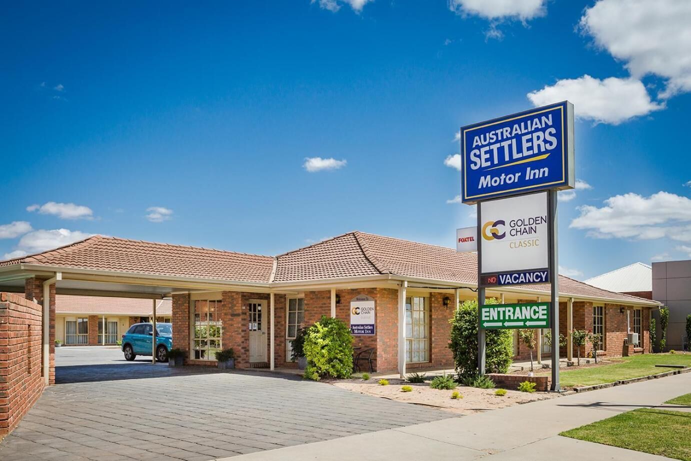 A motel with a covered parking area, a brick building, and a sign indicating it's a motor inn.