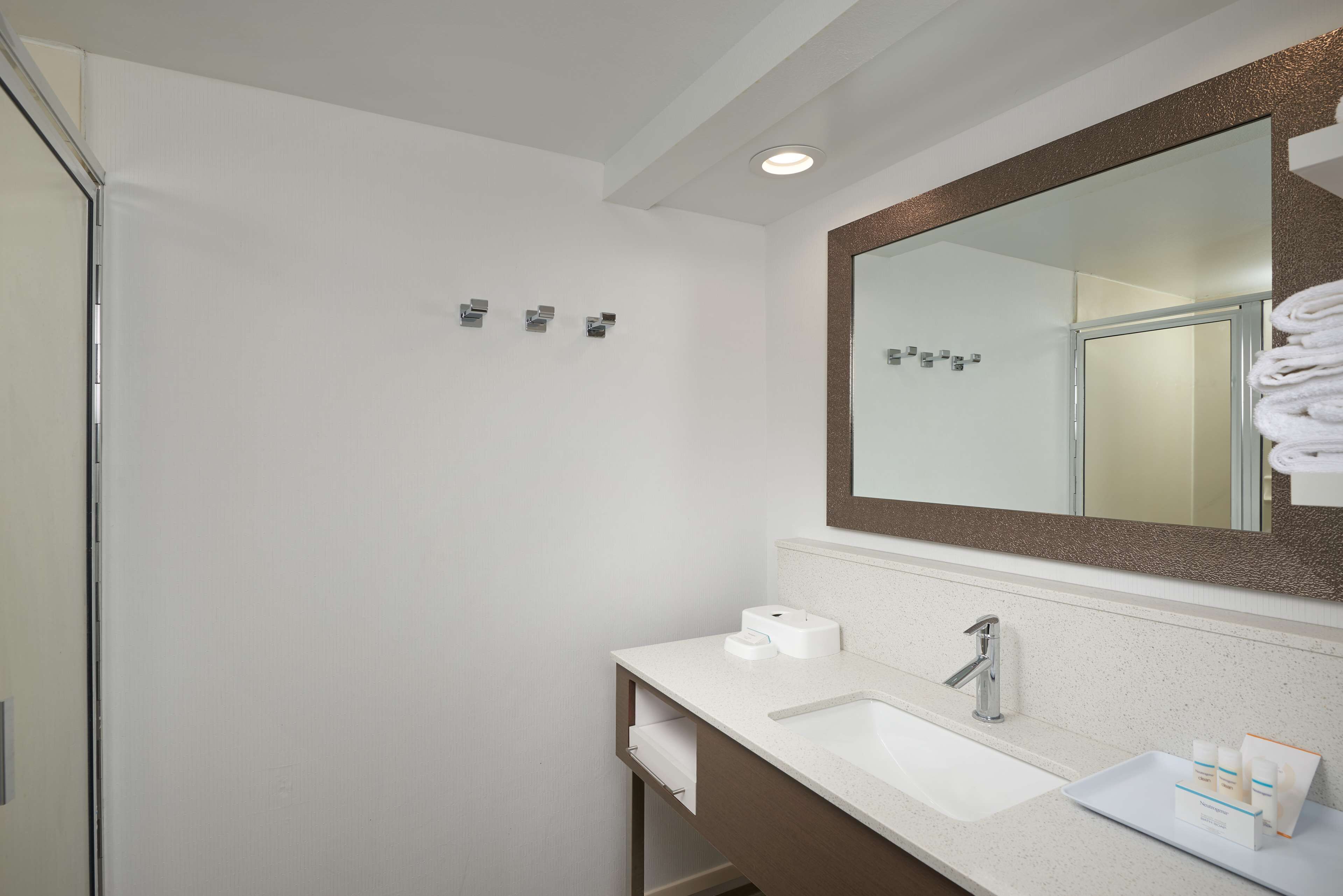 A bathroom with a white sink, a large mirror, and a towel rack.