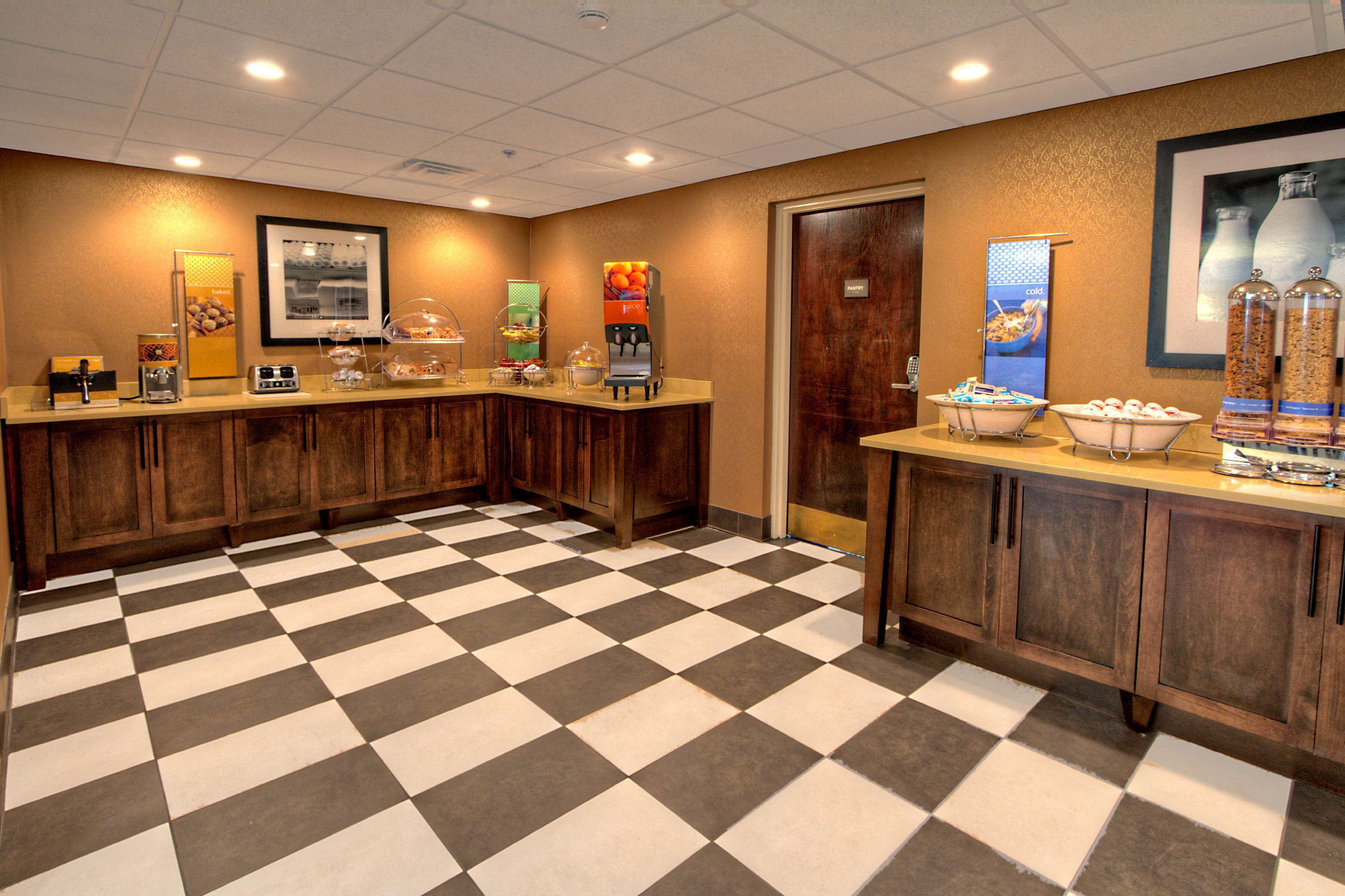 A hotel lobby with a checkered floor, a coffee station, and a food display.