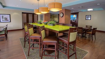 A dining area with a long table, multiple chairs, and hanging pendant lights.