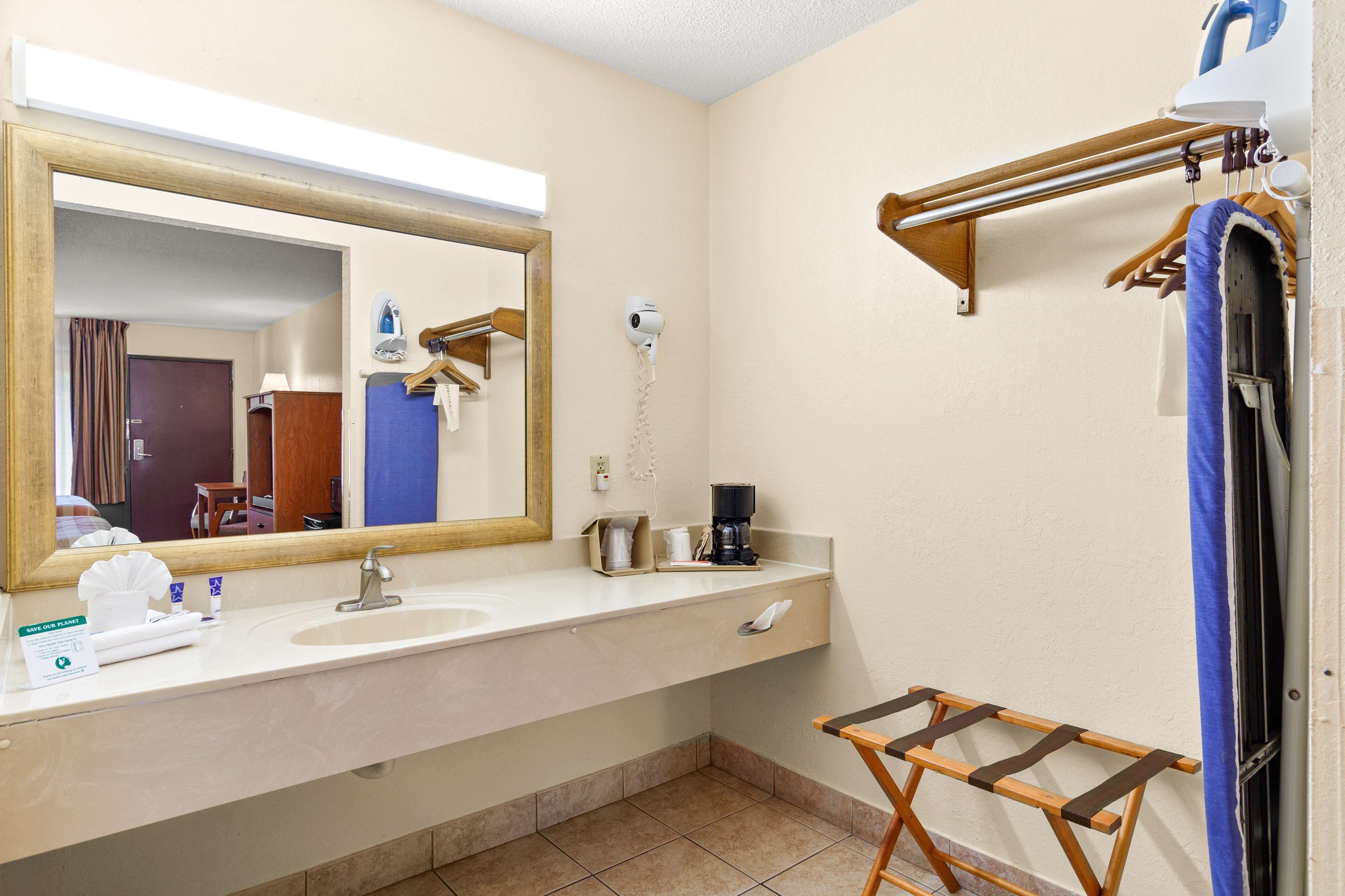Un baño con lavamanos, espejo, toallero y tendedero.