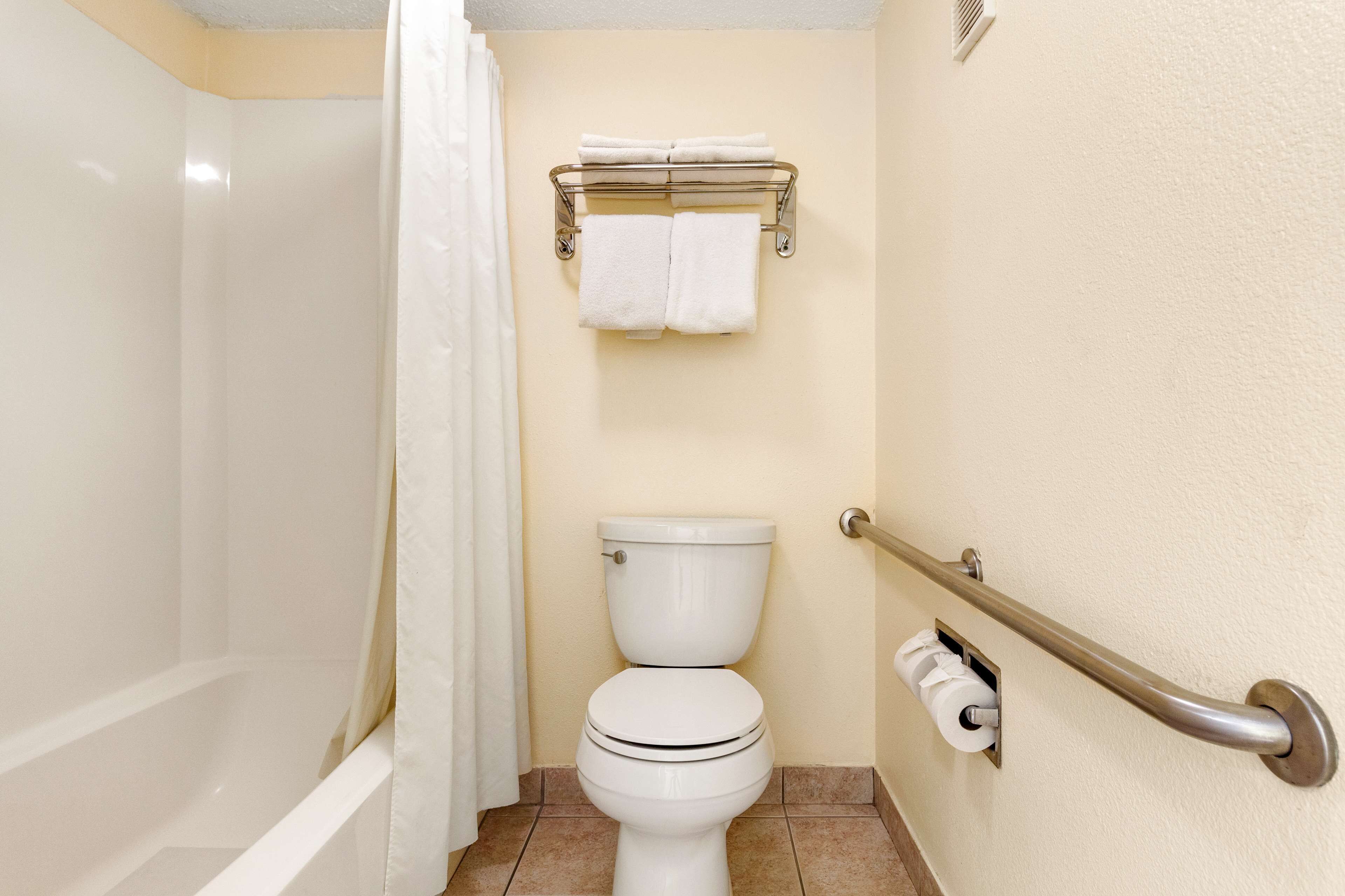 A bathroom with a bathtub, toilet, and a towel rack.