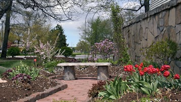 A garden with a stone bench, flowering plants, and a stone wall.