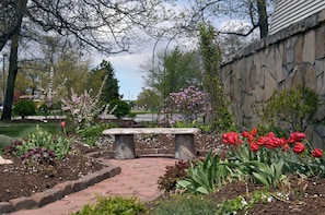 A garden with a stone bench, flowering plants, and a stone wall. - Red Roof Inn Elkhart (Elkhart)