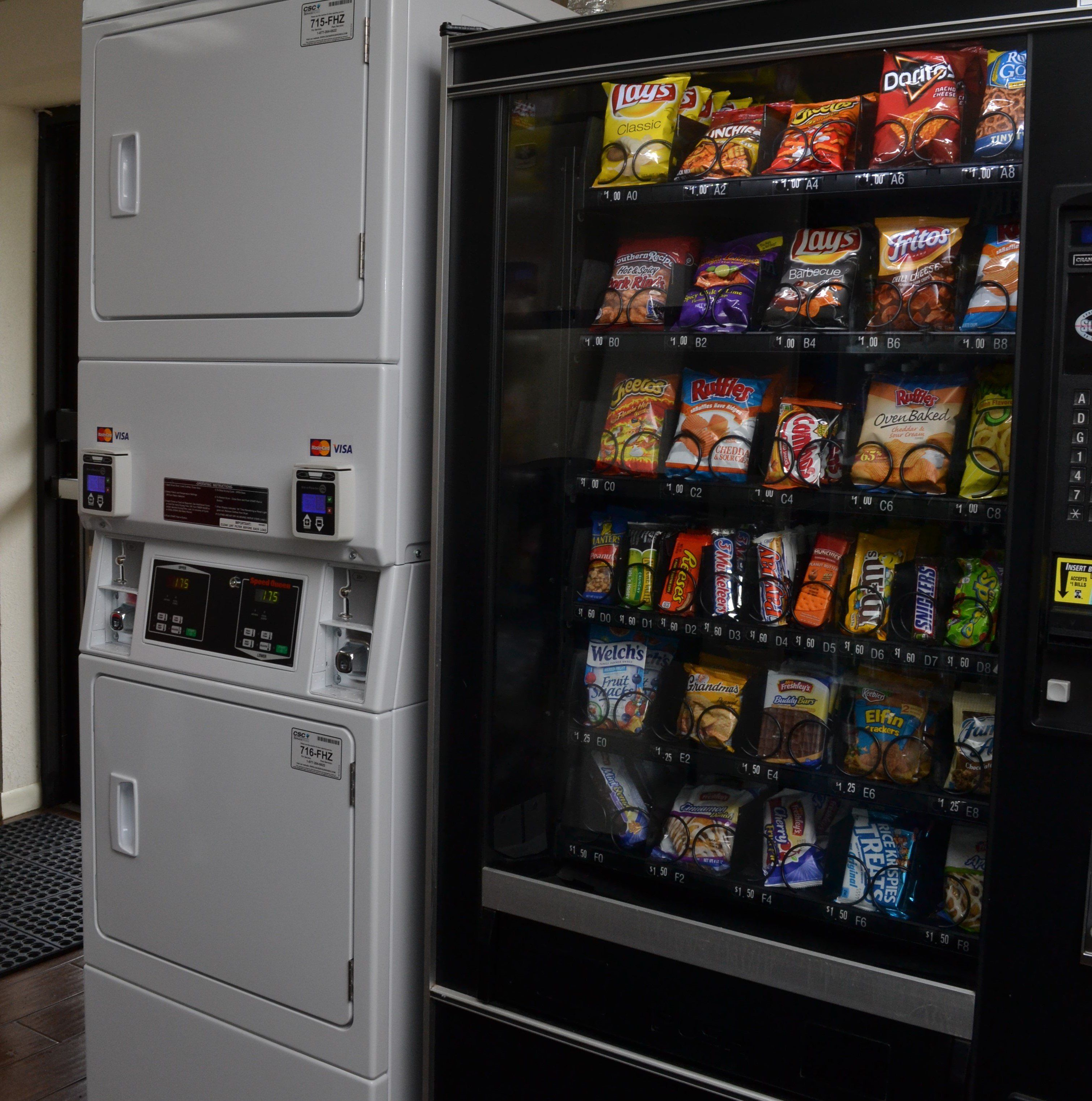 A vending machine stocked with snacks and beverages, with a payment terminal below it.