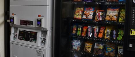 Máquina expendedora llena de refrigerios y bebidas, con un terminal de pago debajo.