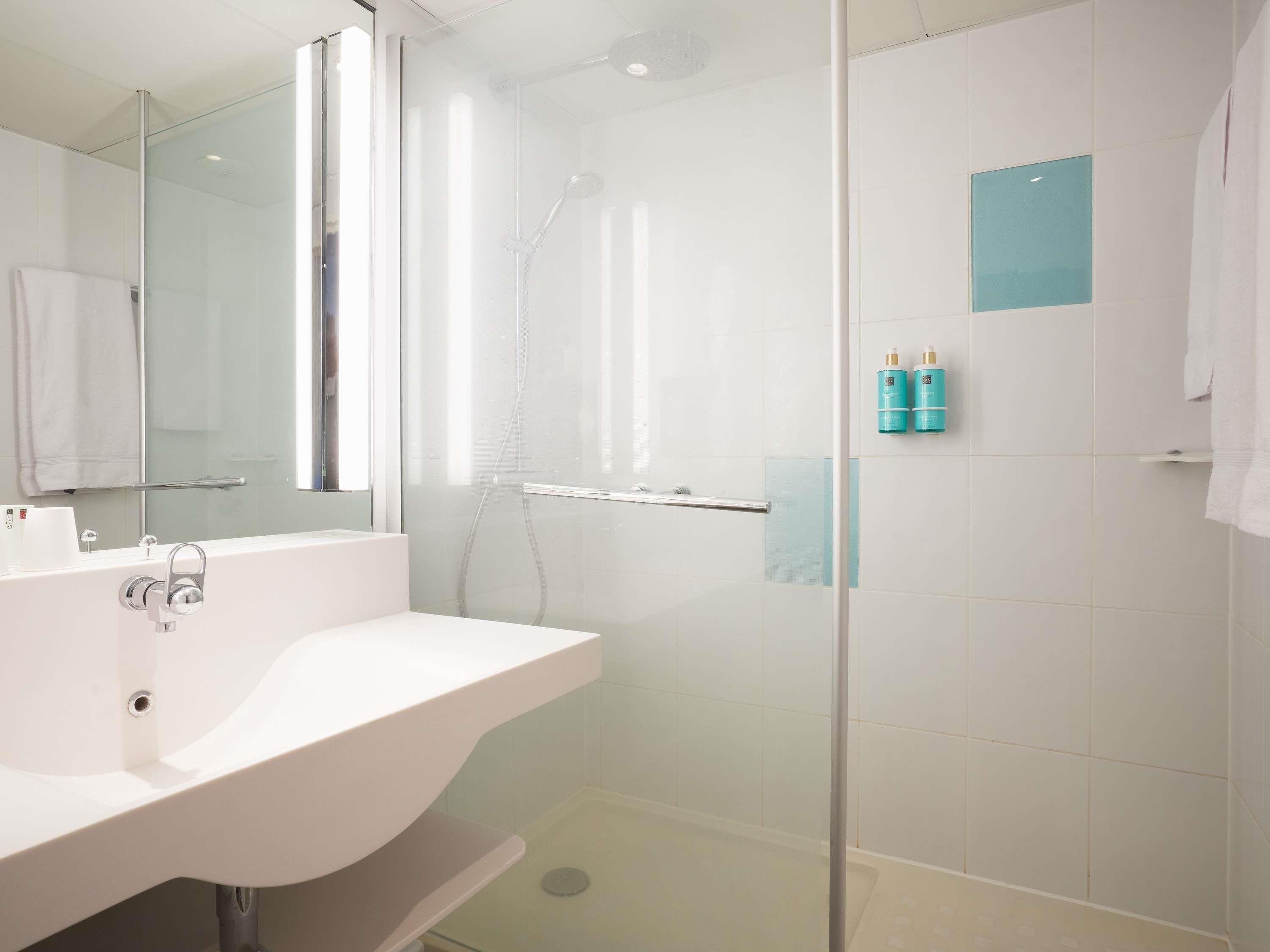 Un baño moderno con cabina de ducha de vidrio, un lavabo blanco y un espejo.